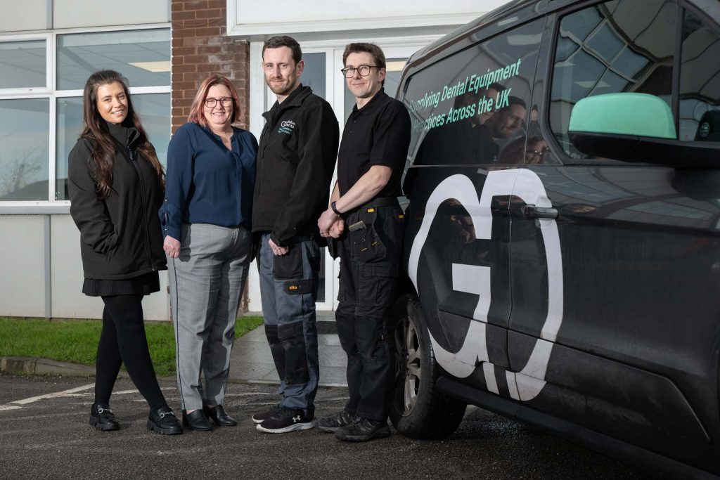 Group photo of dental team standing outside a building next to a branded van.