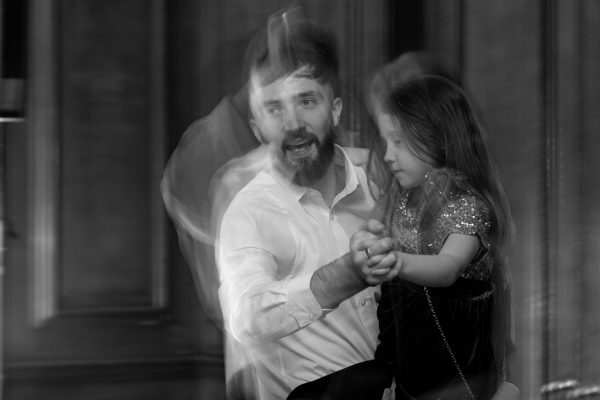 Black and white image with motion blur showing a father and daughter dancing joyfully, evoking energy and emotion.