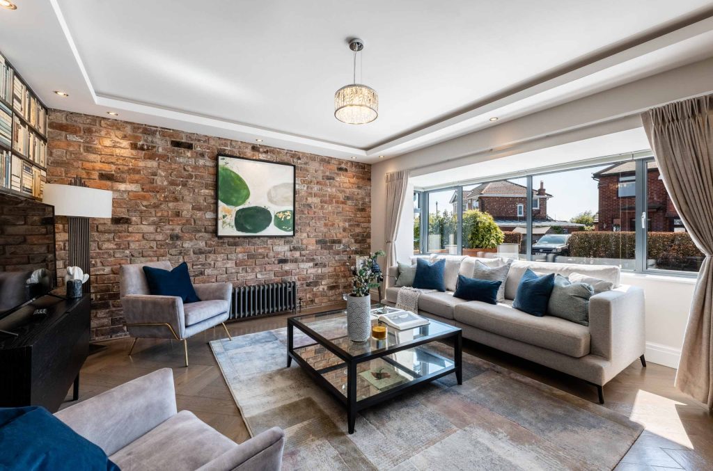 Bright living area with textured brick feature wall, neutral seating, and glass coffee table in natural light.