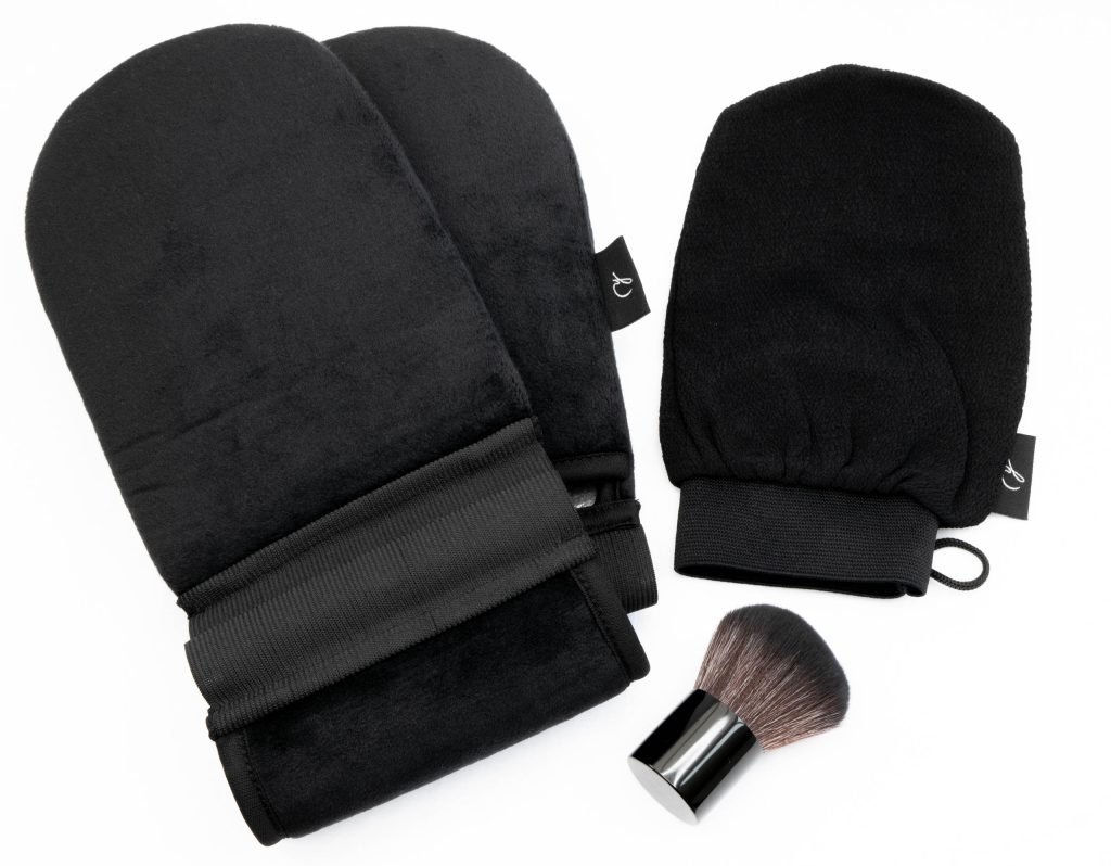 Black self-tanning mitts and kabuki brush positioned together for a clean, minimalist product photo.