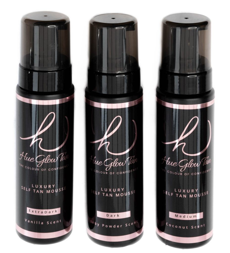 Trio of black tanning mousse bottles labelled Extra Dark, Dark, and Medium, aligned on a white surface.