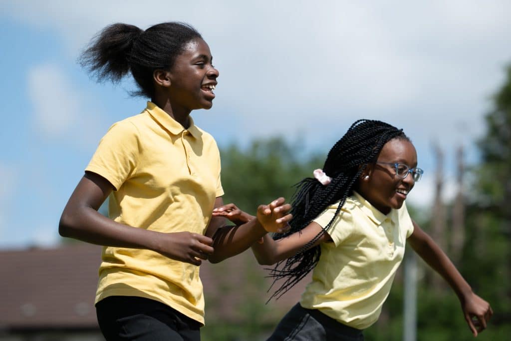 Two girls joyfully running outdoors.